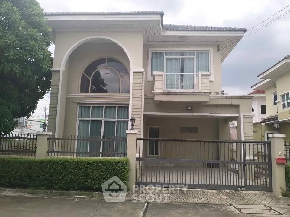 Elegant two-story house with large windows and gated driveway in suburban neighborhood.