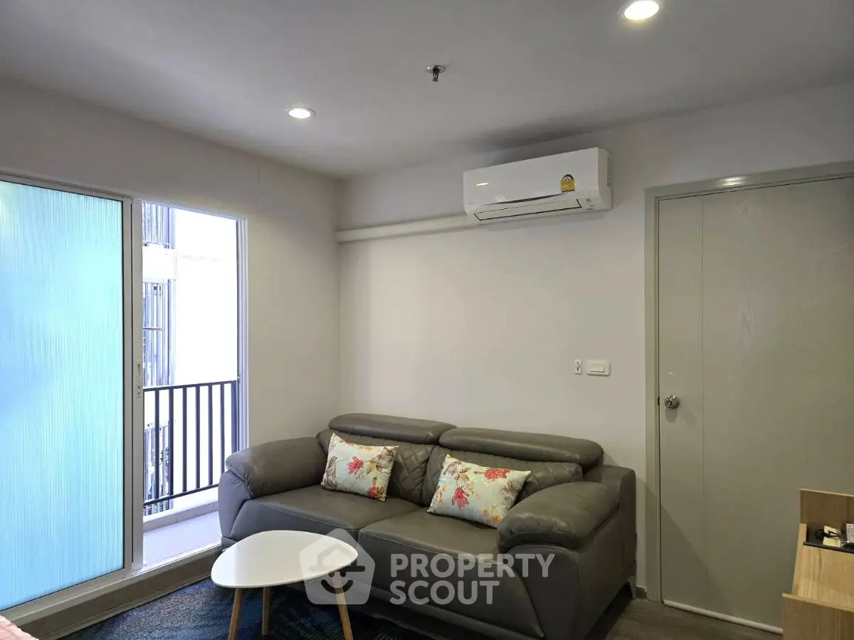 Modern living room with cozy sofa and air conditioning, featuring a small balcony view.