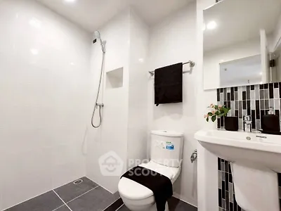 Modern bathroom with sleek design, featuring a shower, toilet, and stylish sink area.