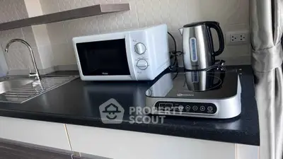 Modern kitchen with microwave, kettle, and induction cooktop on sleek countertop