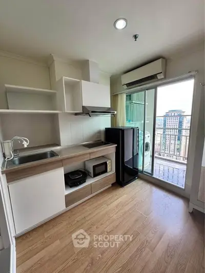Modern kitchen with balcony view, featuring sleek cabinetry and appliances in a high-rise apartment.
