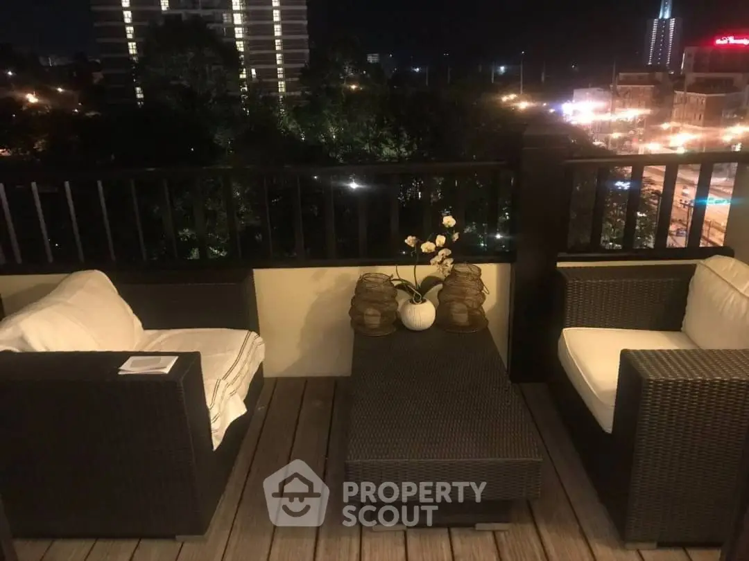 Charming rooftop terrace with cozy seating and city night view.