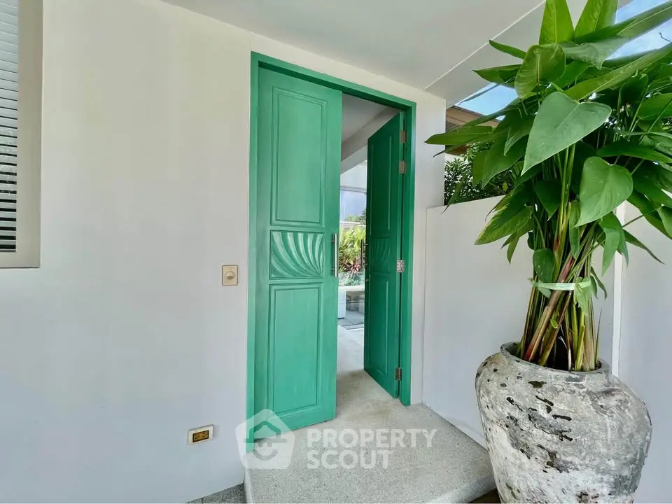 Charming entrance with vibrant green door and lush potted plant, inviting ambiance for modern homes.