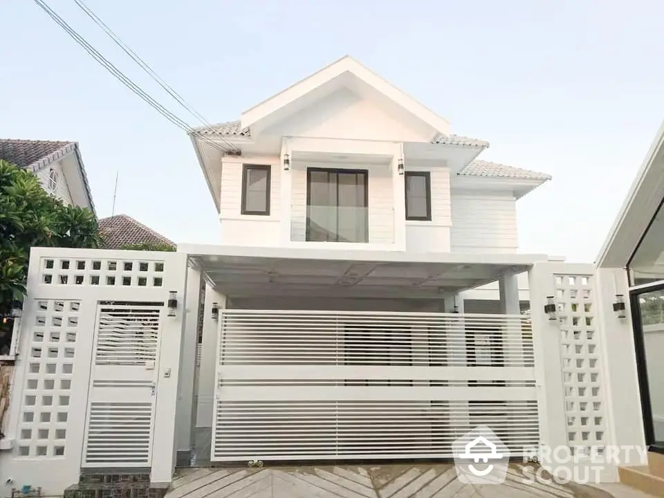 Charming two-story white house with a secure gated entrance and modern design, featuring a spacious garage and elegant balcony.