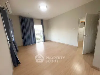 Spacious empty bedroom with wooden flooring and large window