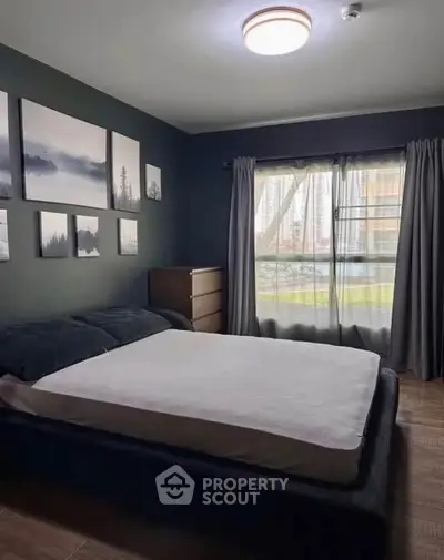 Cozy bedroom with modern decor and large window offering natural light.