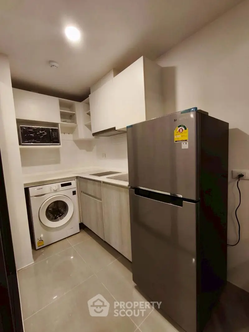 Modern kitchen with sleek appliances including fridge and washing machine, perfect for urban living.