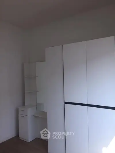 Minimalist bedroom with sleek white wardrobe and vanity set, perfect for modern living.