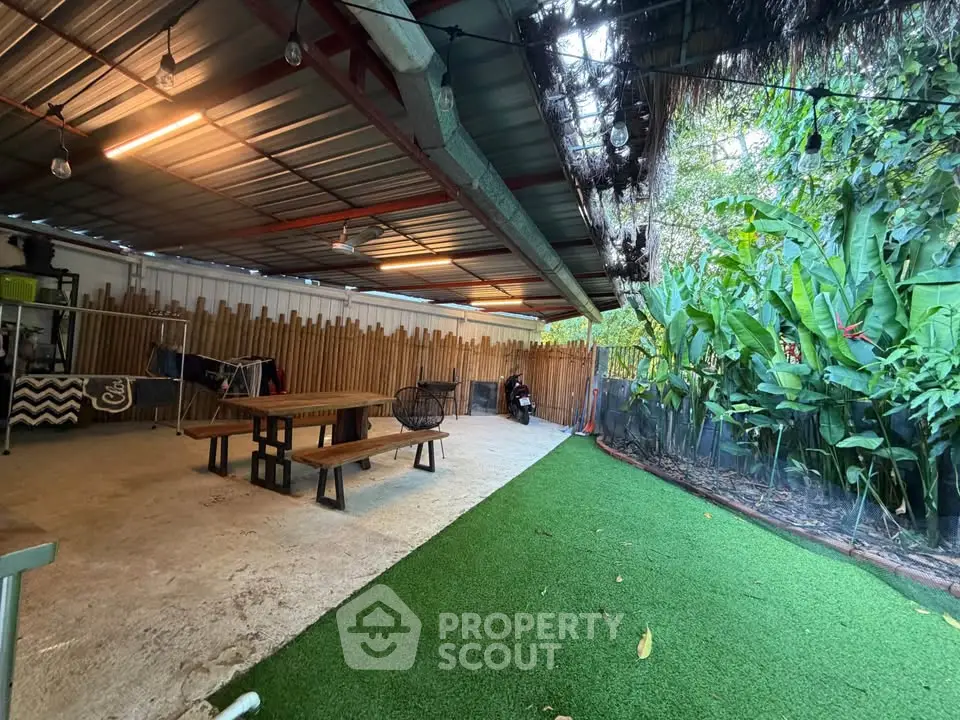 Spacious outdoor area with covered seating and lush greenery, perfect for relaxation and gatherings.