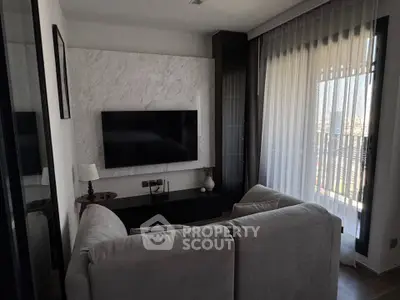 Cozy living room with modern decor and large TV, featuring a comfortable sofa and natural light from large windows.