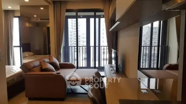 Modern living room with large windows and stylish furniture in a high-rise apartment.