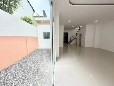 Spacious modern interior with large windows and outdoor gravel area, perfect for natural light lovers.