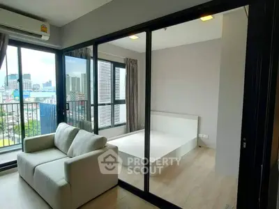 Modern apartment with glass partition, cozy sofa, and city view balcony.