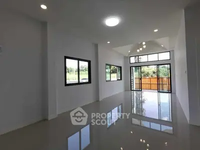 Spacious modern living room with large windows and glossy floor, offering abundant natural light and garden view.