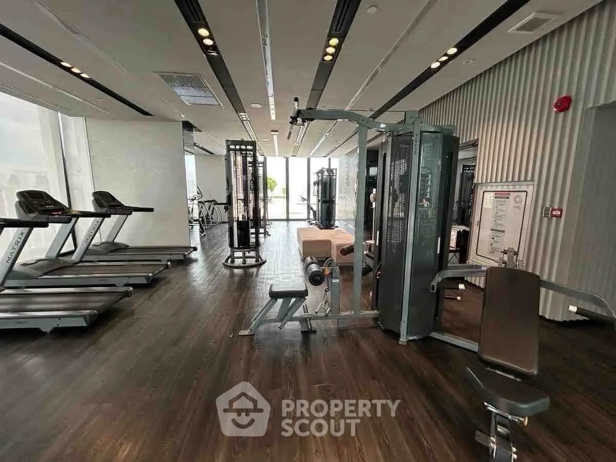 Spacious modern gym with state-of-the-art equipment and large windows for natural light.