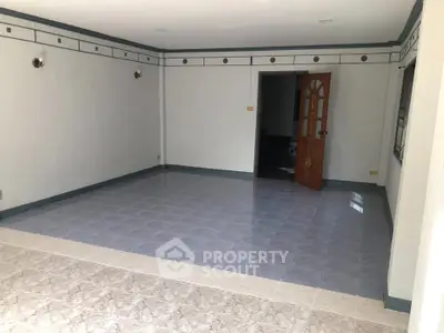 Spacious empty room with tiled flooring and decorative wall trim, ideal for customization.