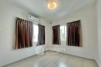 Bright empty room with wooden flooring and large windows, perfect for customization.