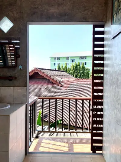 Charming bathroom with balcony view overlooking rooftops and greenery, offering a serene and airy atmosphere.