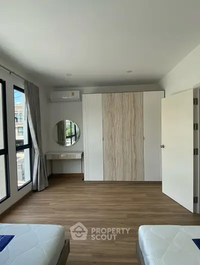 Spacious bedroom with modern design, featuring large windows and elegant wooden flooring.