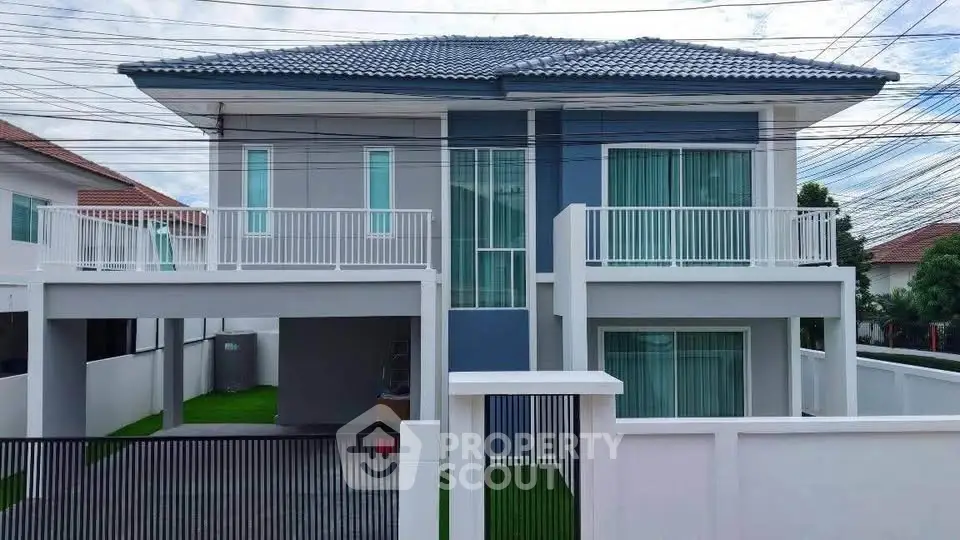 Modern two-story house with sleek design and spacious balcony in a suburban neighborhood.