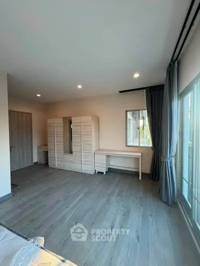 Spacious bedroom with modern wardrobe and large windows offering natural light.