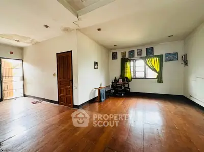 Spacious living room with wooden flooring and natural light, ideal for cozy gatherings.