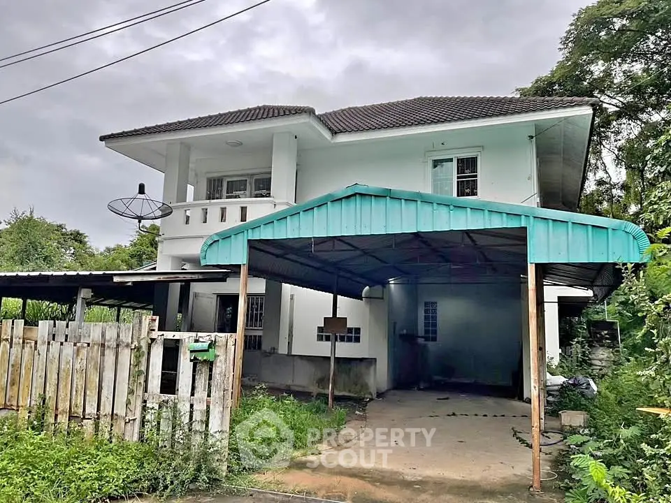 Charming two-story house with carport and lush greenery, perfect for family living.