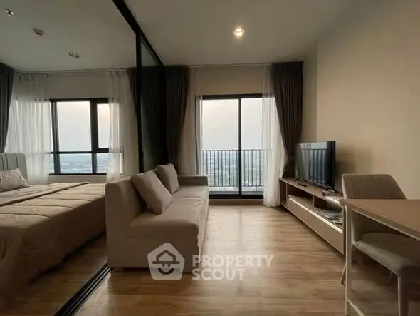 Modern studio apartment with large windows and balcony offering stunning city views.