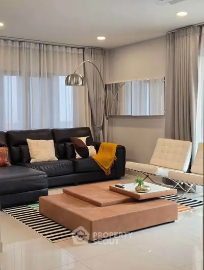 Modern living room with stylish furniture and elegant decor, featuring a black leather sofa and chic lighting.