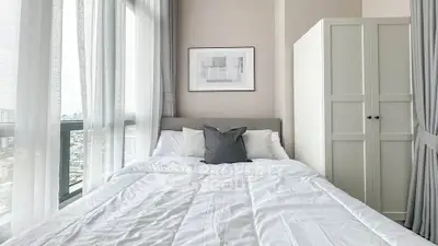 Bright and cozy bedroom with large window and modern decor in a high-rise apartment.