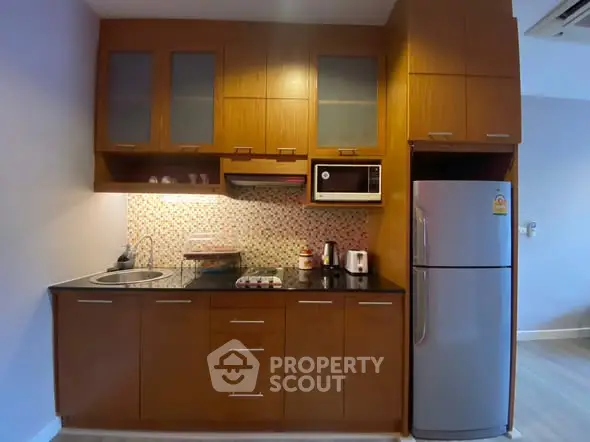 Modern kitchen with wooden cabinets, sleek appliances, and mosaic backsplash in cozy apartment.