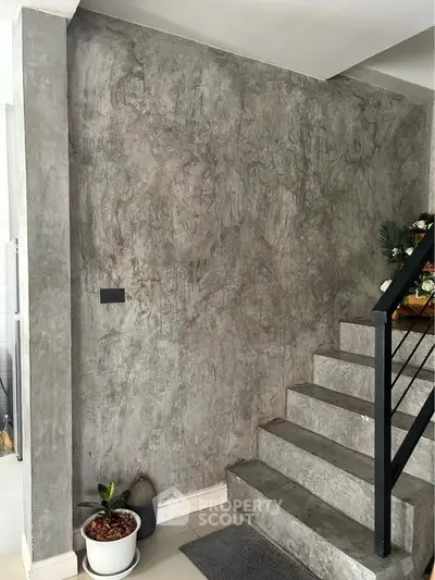 Modern concrete staircase with sleek railing and potted plants, perfect for contemporary homes.