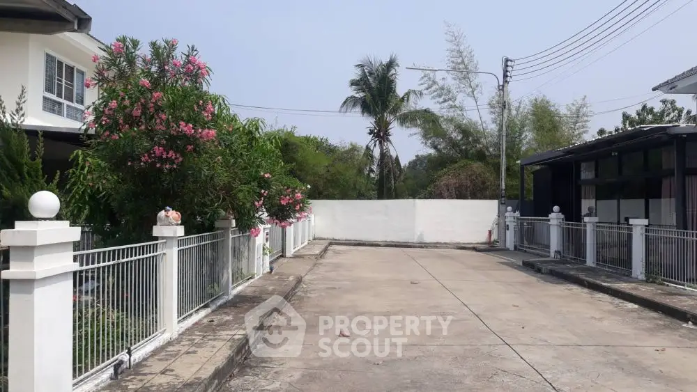 Charming residential driveway with lush greenery and modern fencing