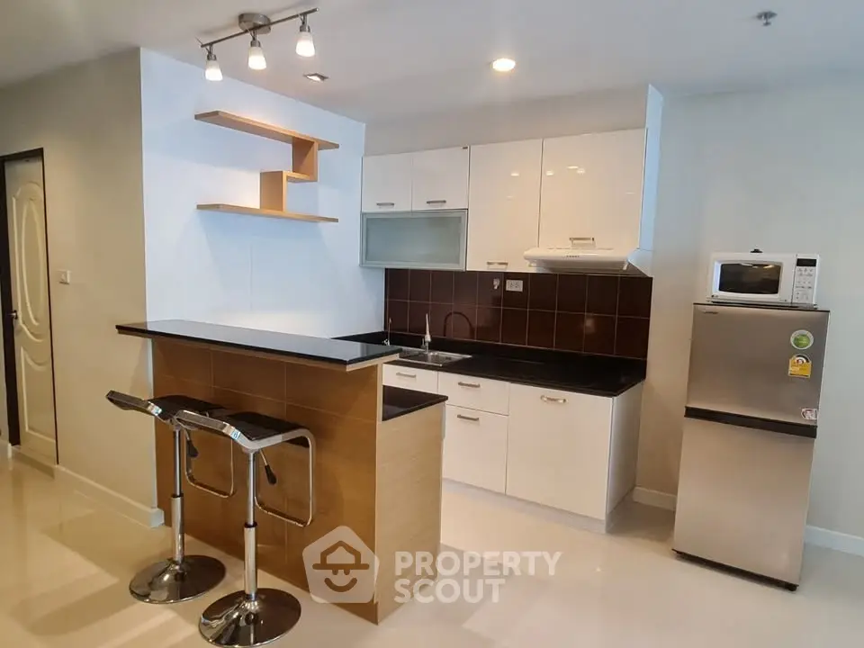 Modern kitchen with sleek cabinetry, breakfast bar, and stainless steel appliances in a stylish apartment.