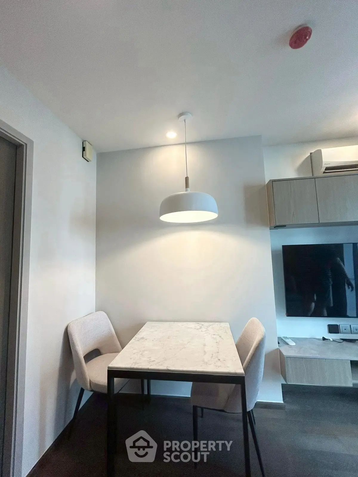 Modern dining area with sleek table and chairs, featuring stylish lighting and wall-mounted TV.