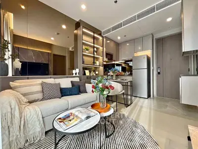 Modern living room with open kitchen, stylish decor, and cozy seating area in a contemporary apartment.
