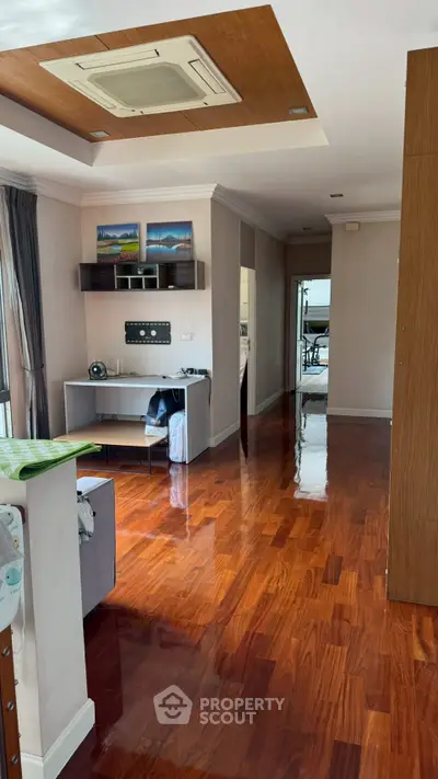 Spacious modern living area with polished wooden floors and stylish ceiling design.