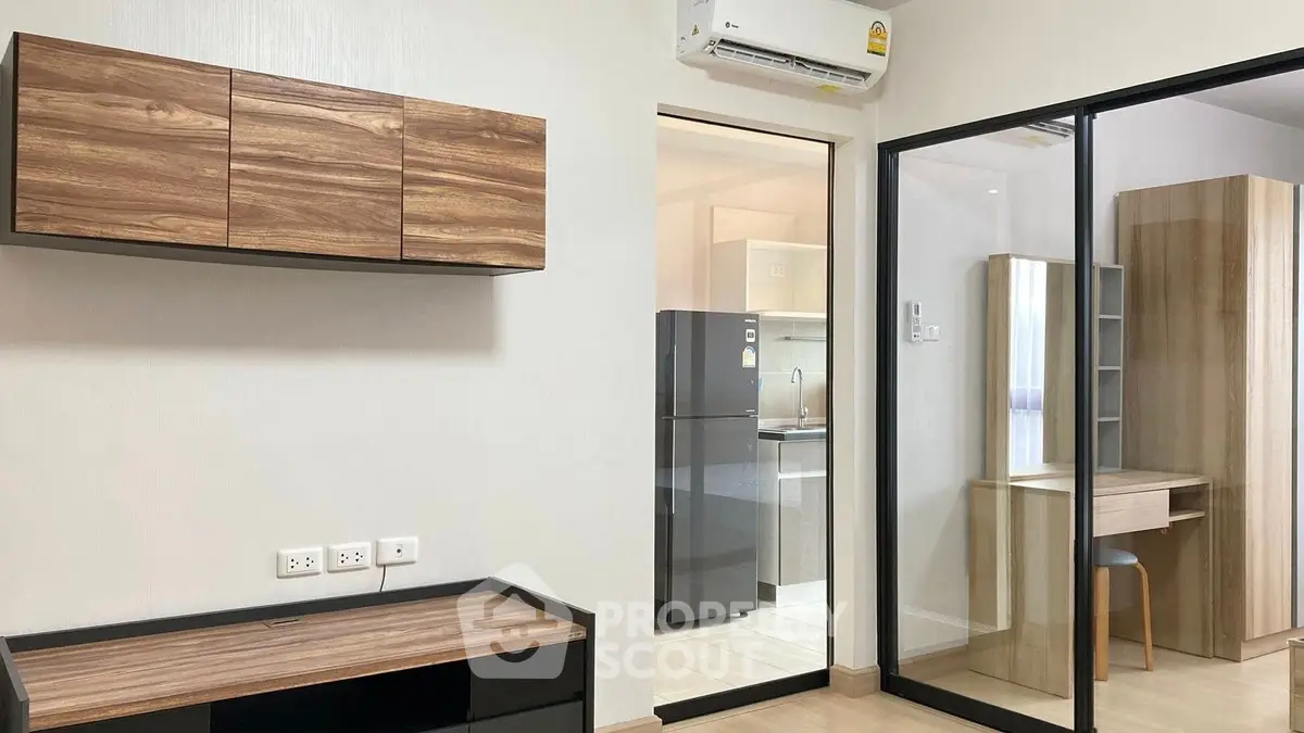 Modern apartment interior with sleek wooden cabinets and glass sliding doors