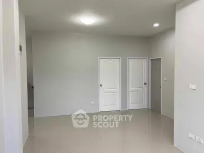 Spacious empty room with glossy tiled floor and white doors, ideal for customization.