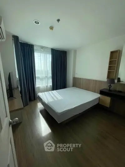Spacious bedroom with natural light and modern furnishings in a stylish apartment.