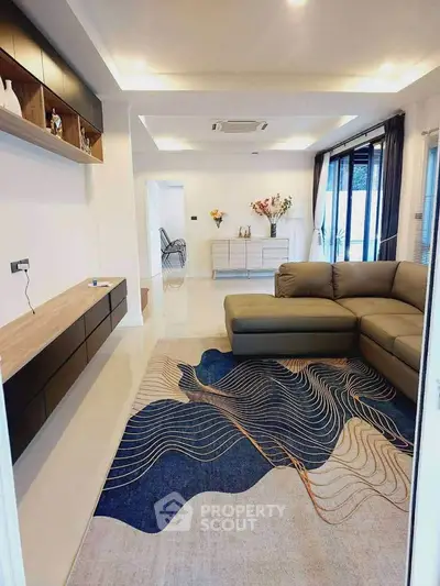 Modern living room with stylish rug and sectional sofa, featuring open layout and elegant decor.