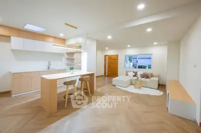 Modern open-plan living room and kitchen with stylish wooden flooring and contemporary furniture.