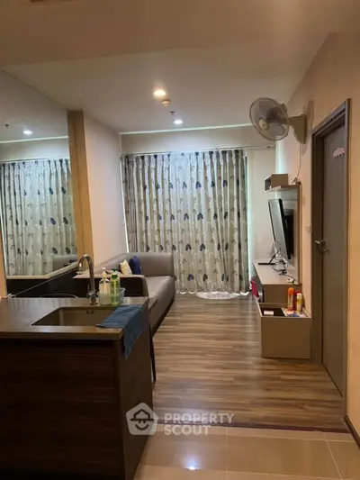 Modern living room with open kitchen, cozy sofa, and stylish decor in a contemporary apartment.