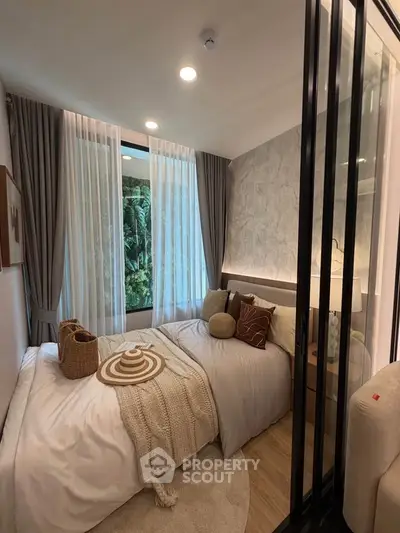 Cozy bedroom with modern decor and large window overlooking lush greenery, perfect for relaxation.