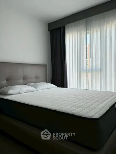 Modern bedroom with large window and elegant curtains, showcasing a comfortable bed in a stylish setting.