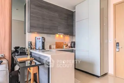 Modern kitchen with sleek cabinetry and compact design, featuring a coffee machine and stylish decor.