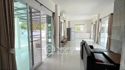 Spacious open-plan living room with large windows and modern kitchen