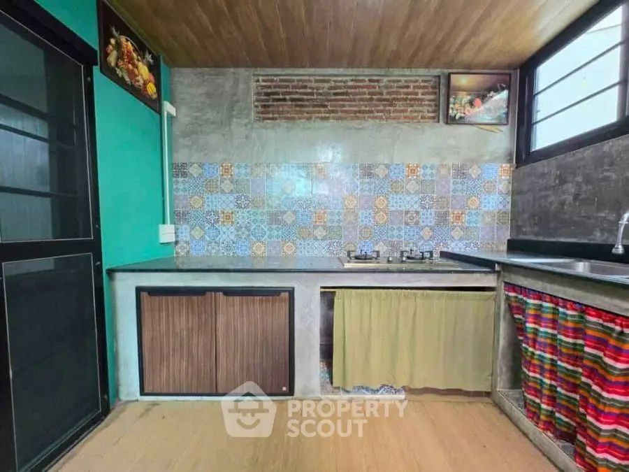 Charming rustic kitchen with colorful tiles and modern gas stove.