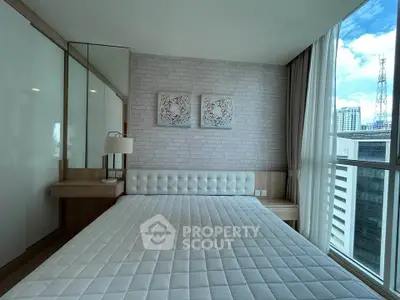 Modern bedroom with large windows and city view, featuring stylish decor and ample natural light.