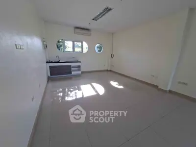 Spacious open-plan room with modern kitchenette and natural light.